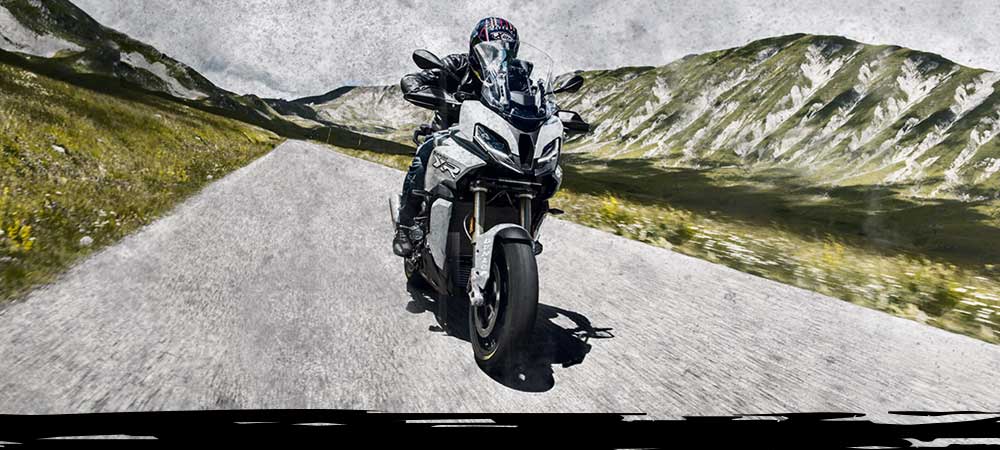BMW S 1000 XR riding on Dunlop Mutant tyres with mountains in the background