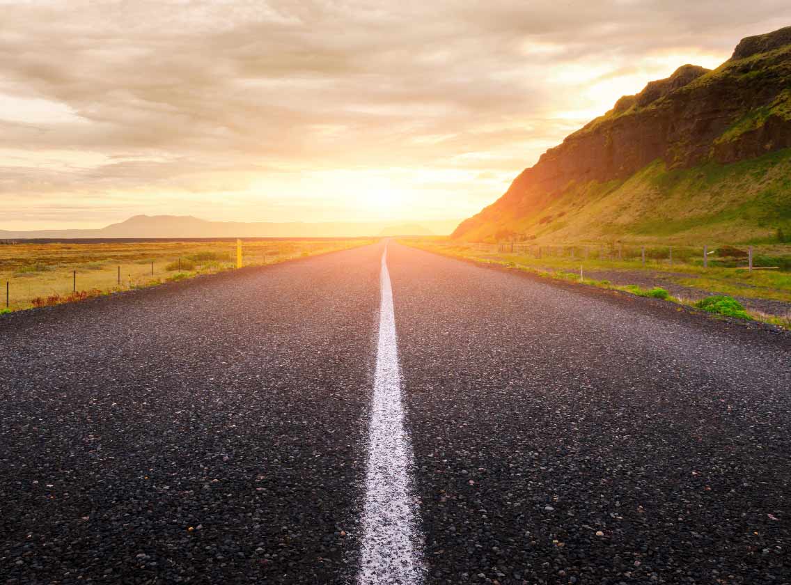 Sun rising over road through the Icelandic countryside