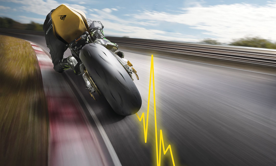Neumático Hyperport Dunlop GP Racer D212 en uso en una pista de carreras con línea de pulso amarilla
