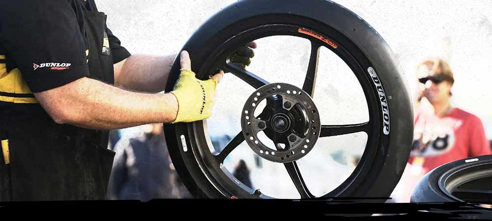 Ingeniero de carreras Dunlop sosteniendo un neumático de carreras Dunlop