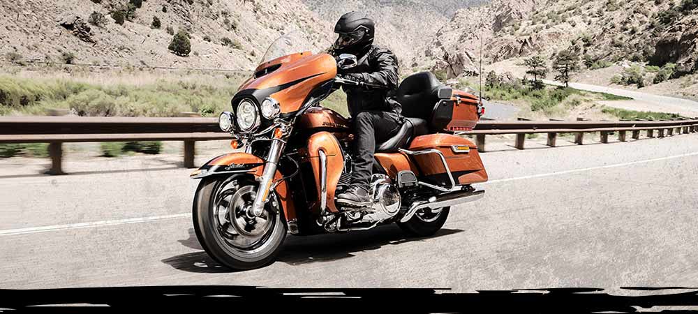 Motard Harley-Davidson à cheval sur des pneus Dunlop à travers les montagnes